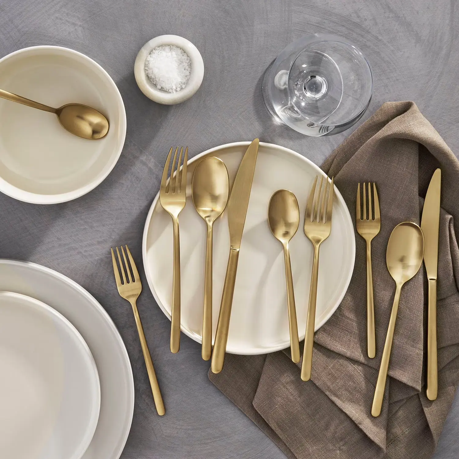 Member's Mark matte gold 20 piece stainless steel flatware set displayed on plate