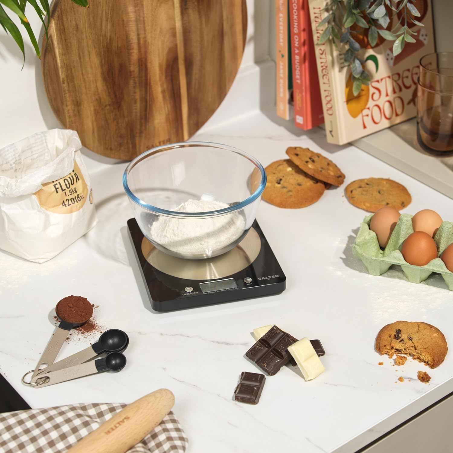 Salter electronic kitchen scale with black body and steel platform holding bowl of flour
