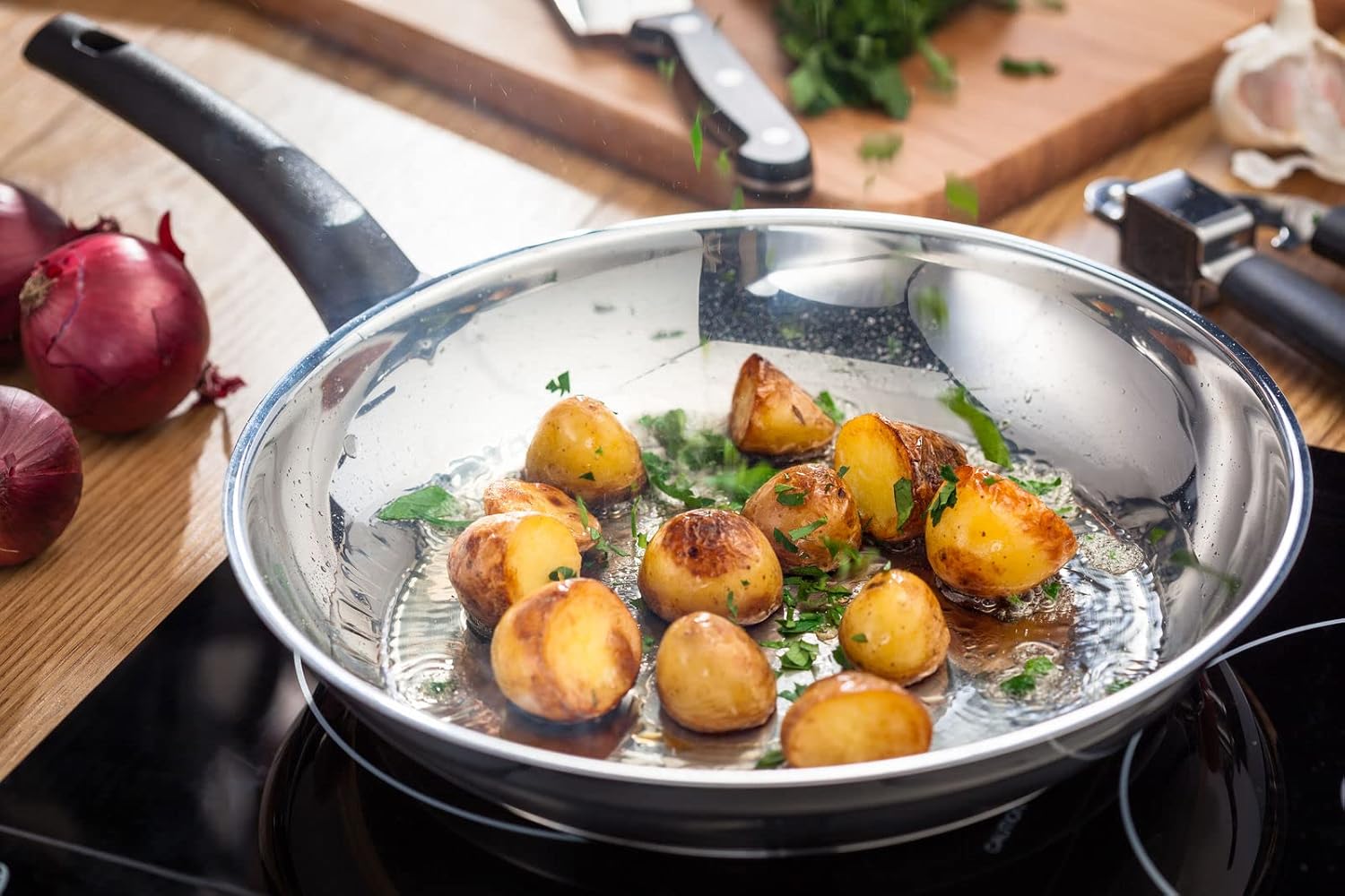 Judge Essentials 24cm stainless steel sauté pan with glass lid containing potatoes